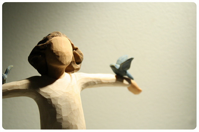 Sculpture en bois d'un personnage recevant deux colombes