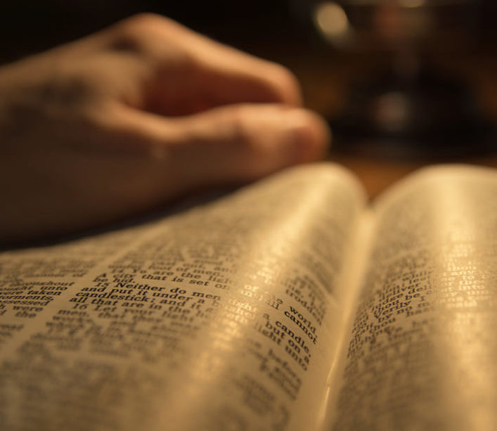 Une Bible tenue par une main et lue à la lumière d