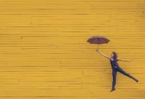 une femme tenant un parapluie semble s'envoller - Photo by Edu Lauton on Unsplash