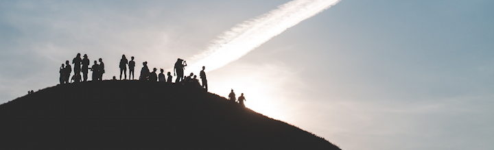 un groupe rassemblé au sommet d'une montagne au lever du jour - Photo by Mariusz Słoński on Unsplash