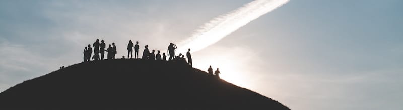 un groupe rassemblé au sommet d'une montagne au lever du jour - Photo by Mariusz Słoński on Unsplash