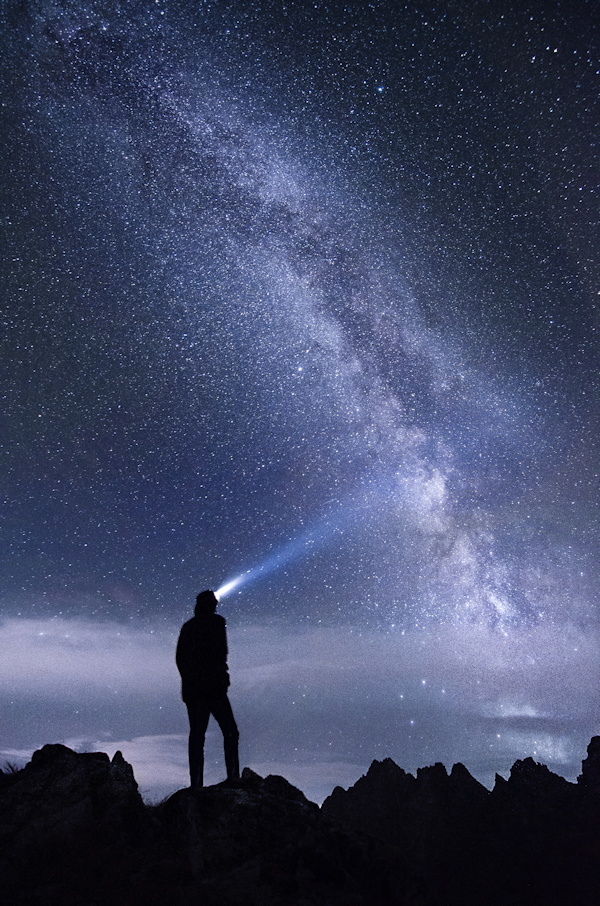 Une personne regarde le ciel étoilé et l'éclaire d'une lampe - photo par stefan stefancik sur unsplash