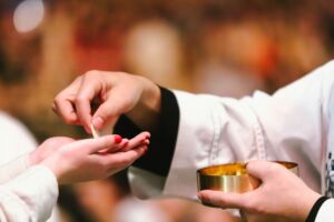 Un prêtre donne le pain à une fidèle lors de la messe - Photo de Jacob Bentzinger sur https://unsplash.com/fr/photos/un-couple-de-personnes-qui-tiennent-une-petite-tasse-sOo0kwPPALU