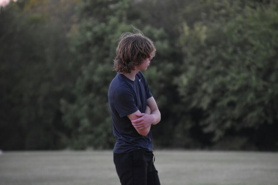 Un garçon adolescent bras croisé, pensif, dans la nature - Photo de Lesli Whitecottonsur https://unsplash.com/fr/photos/un-homme-debout-dans-un-champ-tenant-un-frisbee-RLtR4t7MQsM