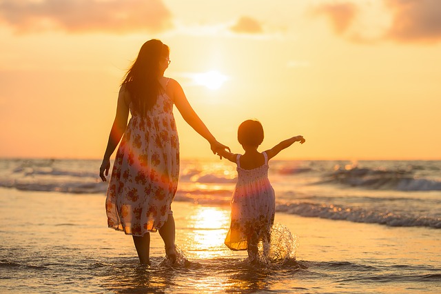Une mère et sa fillette sur un bord de mer et soleil couchant - Image par Sasin Tipchai de Pixabay