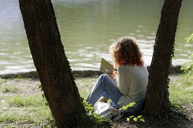 femme lisant dans son psautier devant un lac - Image par Mircea Iancu de Pixabay
