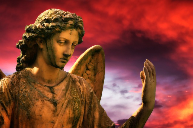 Une statue d'ange, à l'air un peu triste, sur fond de ciel nuageux et rouge - Image par Lolame de Pixabay