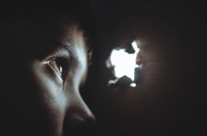 une jeune femme dans l'obscurité regarde par un trou vers la lumière - Image par Free-Photos de Pixabay 