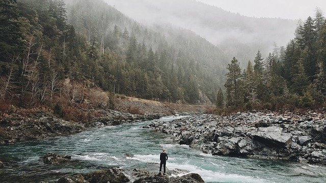 Un homme dans la nature, devant une rivière, des montagnes et de la brume - Image par Free-Photos de Pixabay