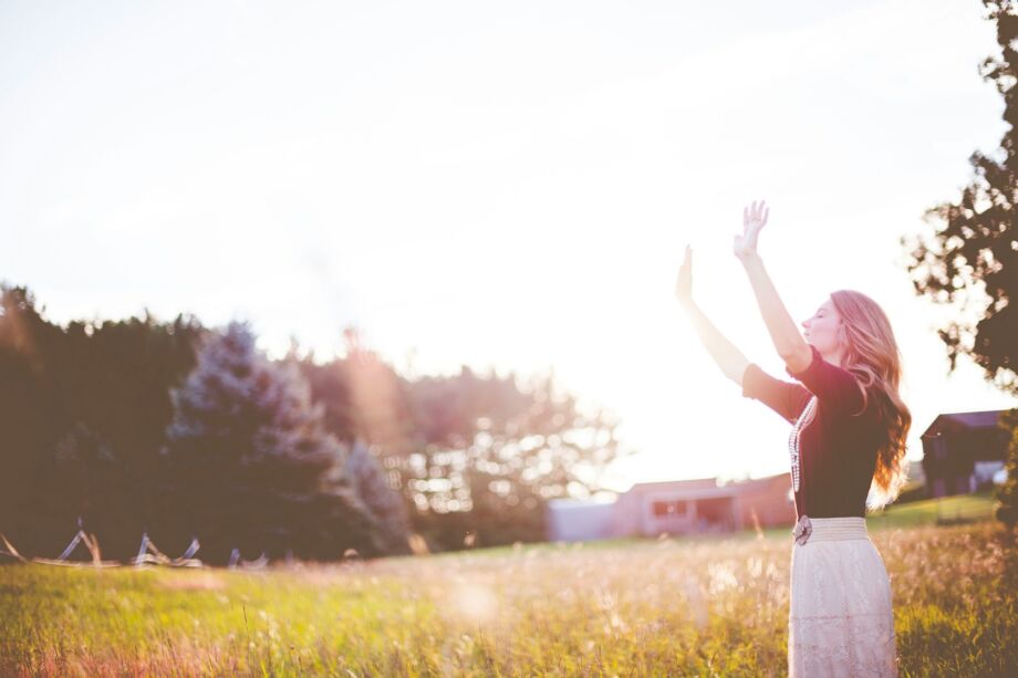 Une femme, en prière, les bras et le visage levés vers le ciel, dans la nature - Photo de Ben Whitesur https://unsplash.com/fr/photos/femme-mains-levees-devant-les-prairies-vertes-TlBF3ZUVTvE