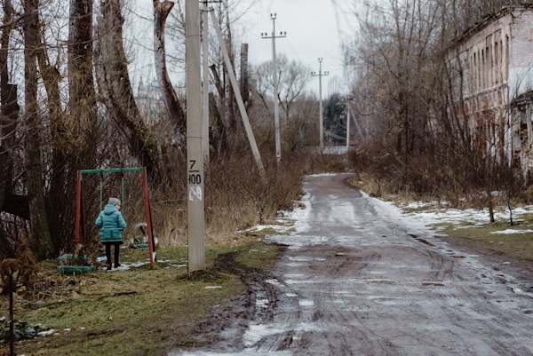 enfant seul sur une balançoire, en bord d'une rout eboueuse - Photo by Artem Maltsev on Unsplash