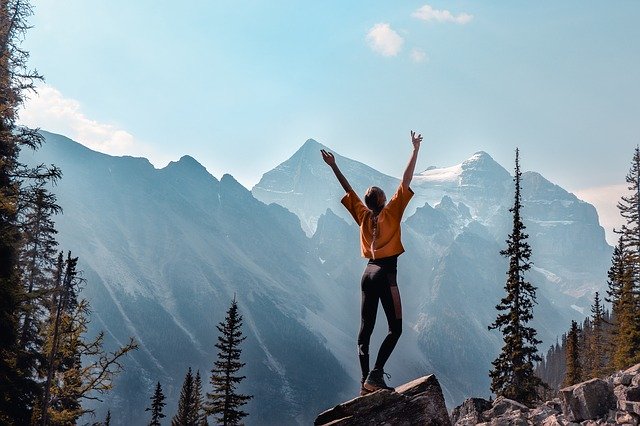 Jeune fille lève les bras au ciel de joie au cours d'une randonnée en montagne - Image par denkendewolke de Pixabay
