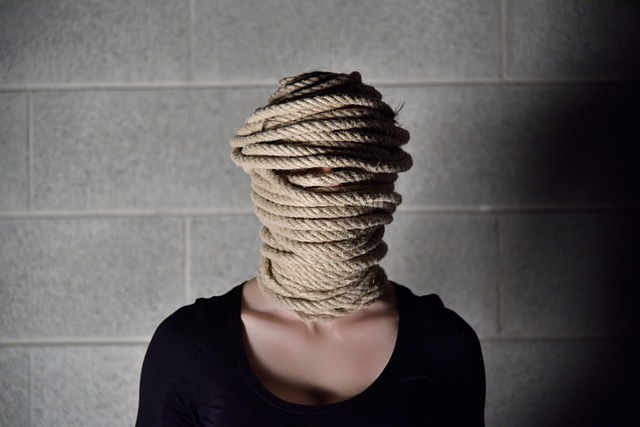 femme avec un visage entièrement prisonnier d'une corde, devant un mur de parpaing - Image par Nino Carè de Pixabay