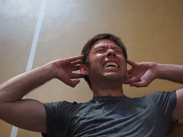 Un homme se bouche les oreilles afin de se protéger d'un son qui lui déchire les tympans - Image par Hans Braxmeier de Pixabay