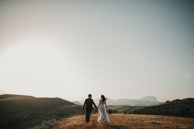 deux mariés dans un pré, devant un beau paysage - Photo by Foto Pettine on Unsplash