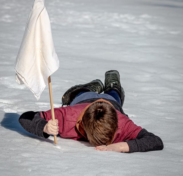 un enfant écroulé dans la neige, brandissant un drapeau blanc - Photo by Jackson Simmer on Unsplash