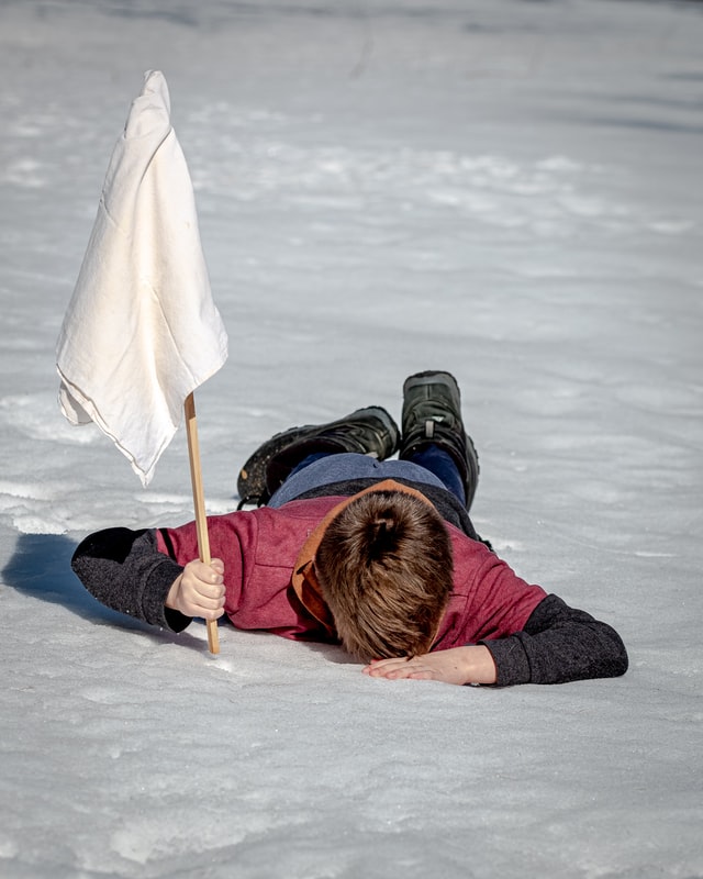 un enfant écroulé dans la neige, brandissant un drapeau blanc - Photo by Jackson Simmer on Unsplash