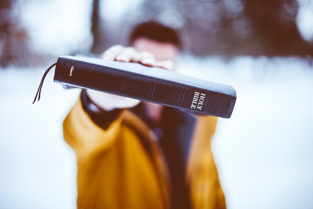 Un homme tend une bible comme violemment - Photo by Ben White on Unsplash