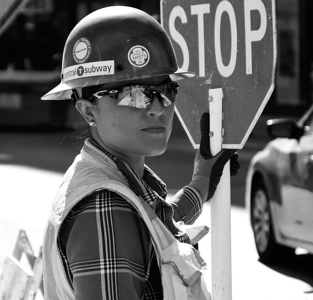 femme en casque de chantier tenant un panneau mobile stop - Photo by Daniele Levis Pelusi on Unsplash