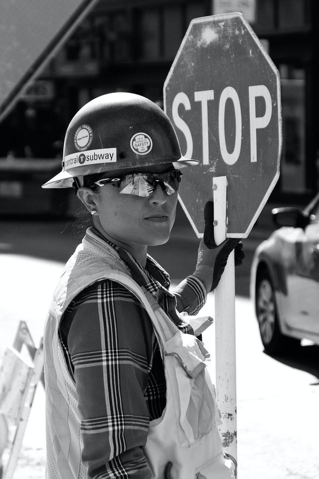 femme en casque de chantier tenant un panneau mobile stop - Photo by Daniele Levis Pelusi on Unsplash