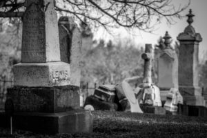 photo en noir et blanc d'un cimetière avec des tombes mal entretenues - Photo by Wendy Scofield on Unsplash