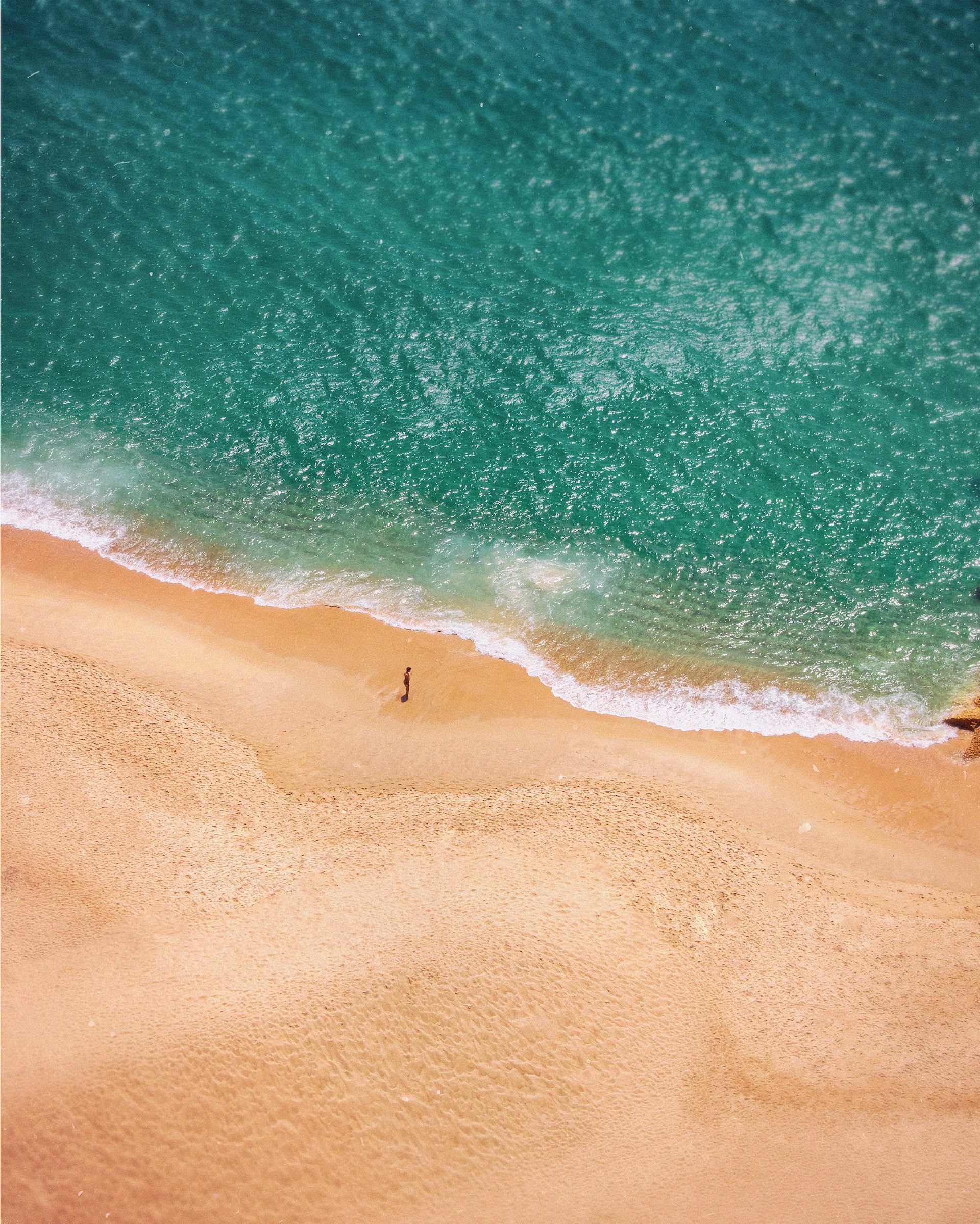une personne seule sur une plage déserte, vue d'avion - Photo by Aurelien Thomas on https://unsplash.com/fr/photos/photographie-dun-plan-deau-OH6wENAdB98