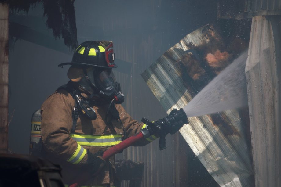 Dans une noire fumée, un pompier avec une lance à incendie projetant de l