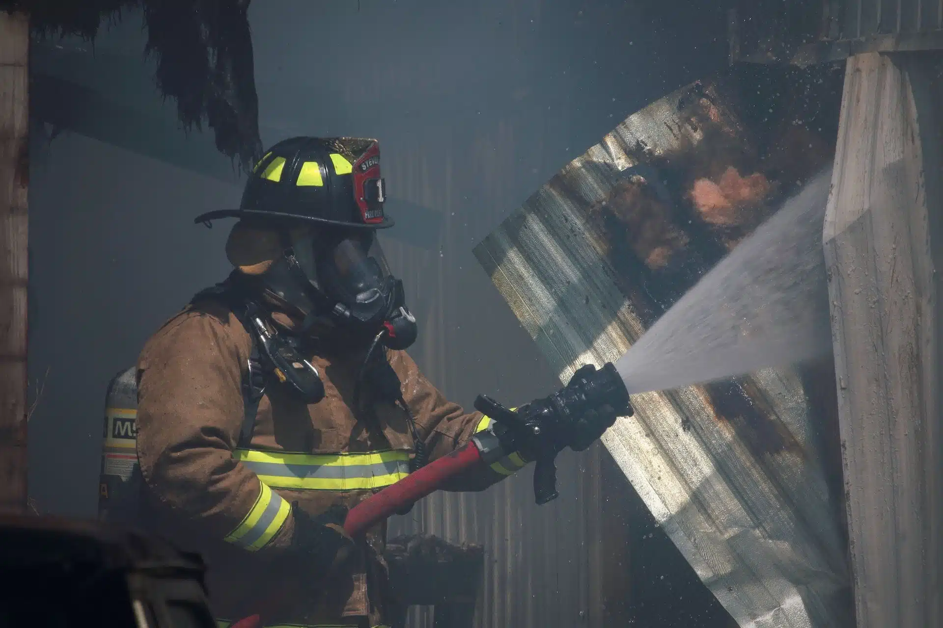 Dans une noire fumée, un pompier avec une lance à incendie projetant de l'eau - Photo by Timothy Eberly on https://unsplash.com/fr/photos/photo-de-mise-au-point-peu-profonde-dun-pompier-utilisant-un-tuyau-deau-rouge-iSmLxCzkoH0