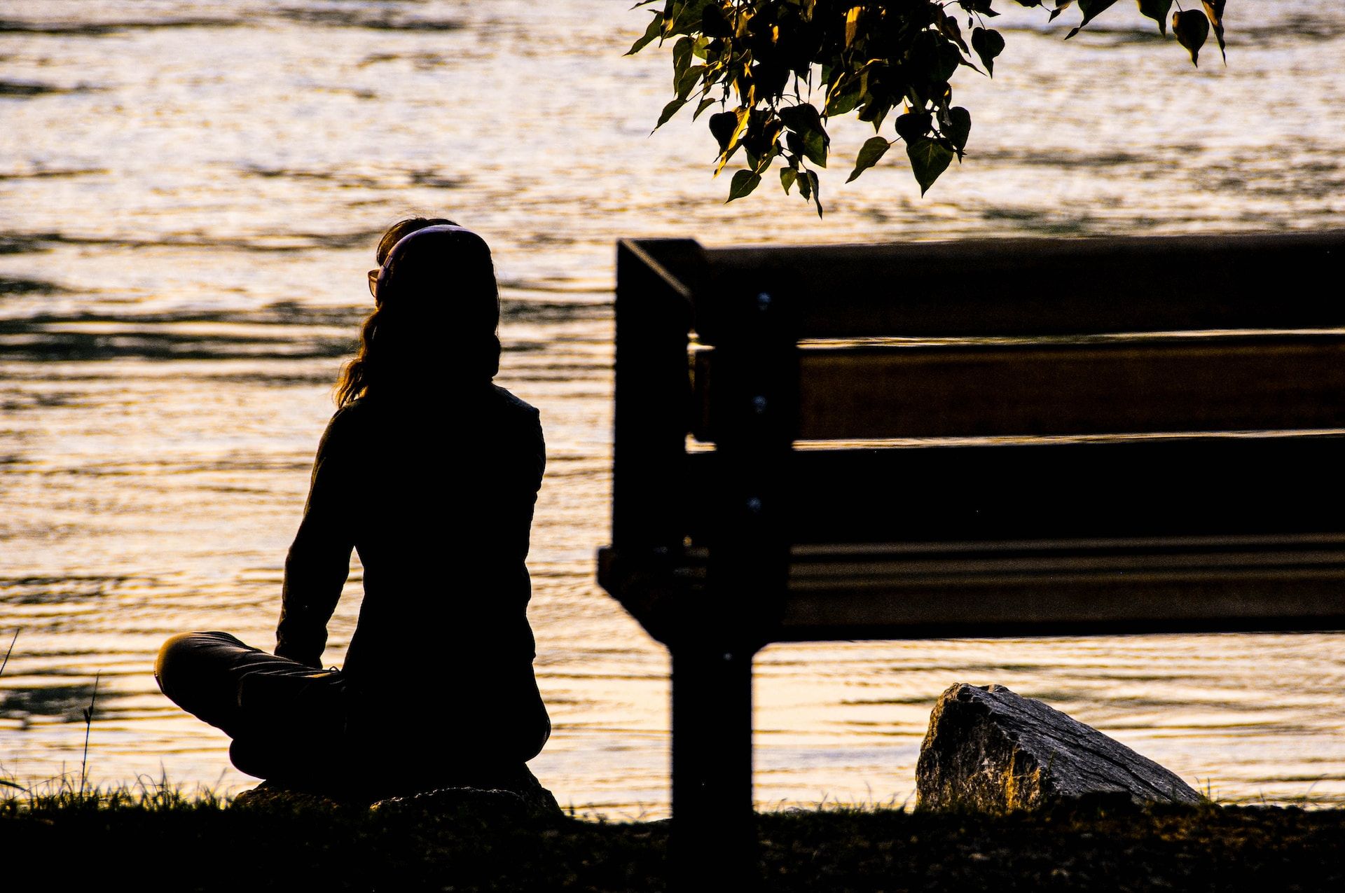 Une femme seule, assise sur le bord d'une rivière au coucher du soleill, un casque sur les aoreilles - Photo by Toni Reed on https://unsplash.com/fr/photos/silhouette-dune-personne-assise-sur-un-banc-pres-dun-plan-deau-pendant-la-journee-BmwEhjQBmyU