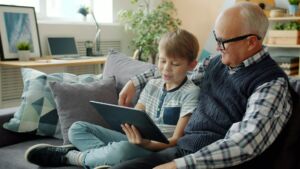 Un grand-père et son petit-fils sur un capapé en train de regarder une tablette - Photo de Vitaly Gariev sur https://unsplash.com/fr/photos/le-grand-pere-et-le-petit-fils-regardent-ensemble-une-tablette-QJVk5Wzl6s8