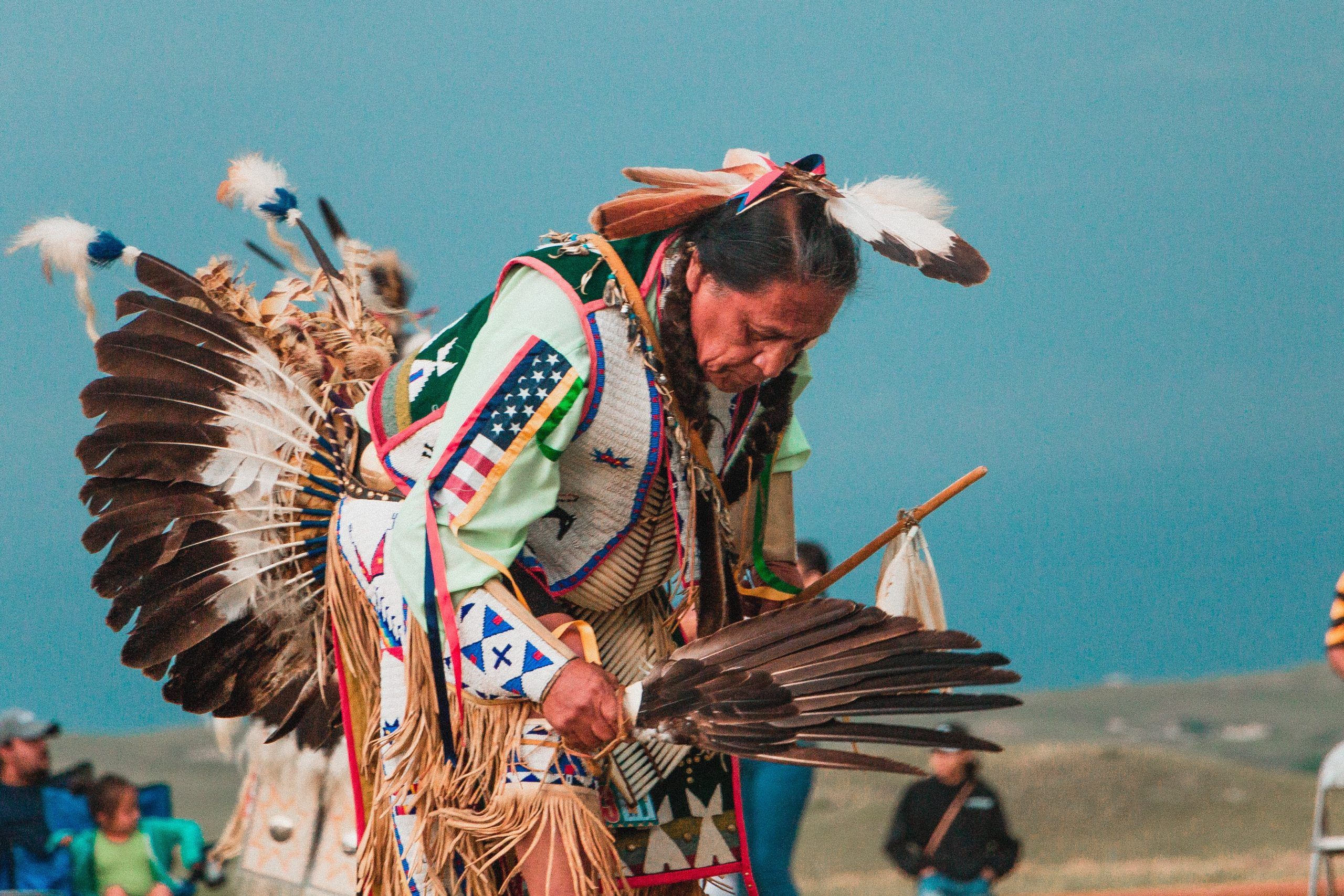 Un amérindien dans le Dakota du Sud, en habits traditionnels avec des plumes, en train de danser - Photo by Andrew James on Unsplash