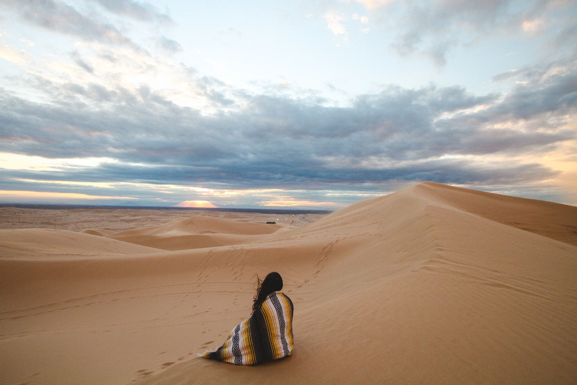 femme assise sous une couverture, contemplant le désert - Photo by Jeremy Bishop on https://unsplash.com/fr/photos/personne-sur-le-dessert-6O3rcoZmx0E