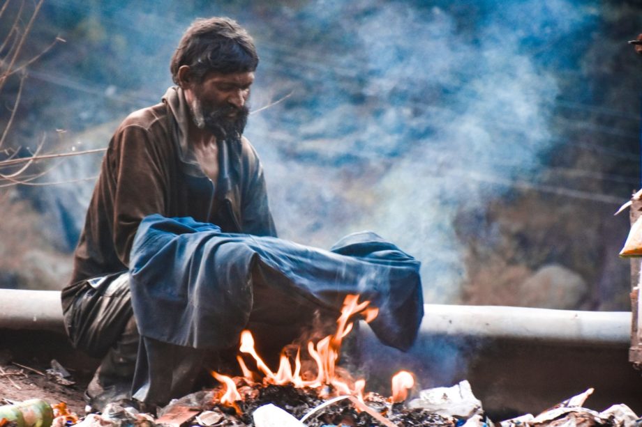 un homme démuni fait sécher son vêtement sur un feu de fortune - Photo by Shail Sharma on https://unsplash.com/fr/photos/homme-chauffant-des-vetements-en-feu-EGPZ7uvcxZA