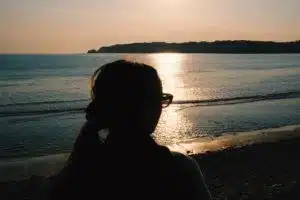 femme regardant un coucher de soleil sur l'océan - Photo by Luke Moss on Unsplash