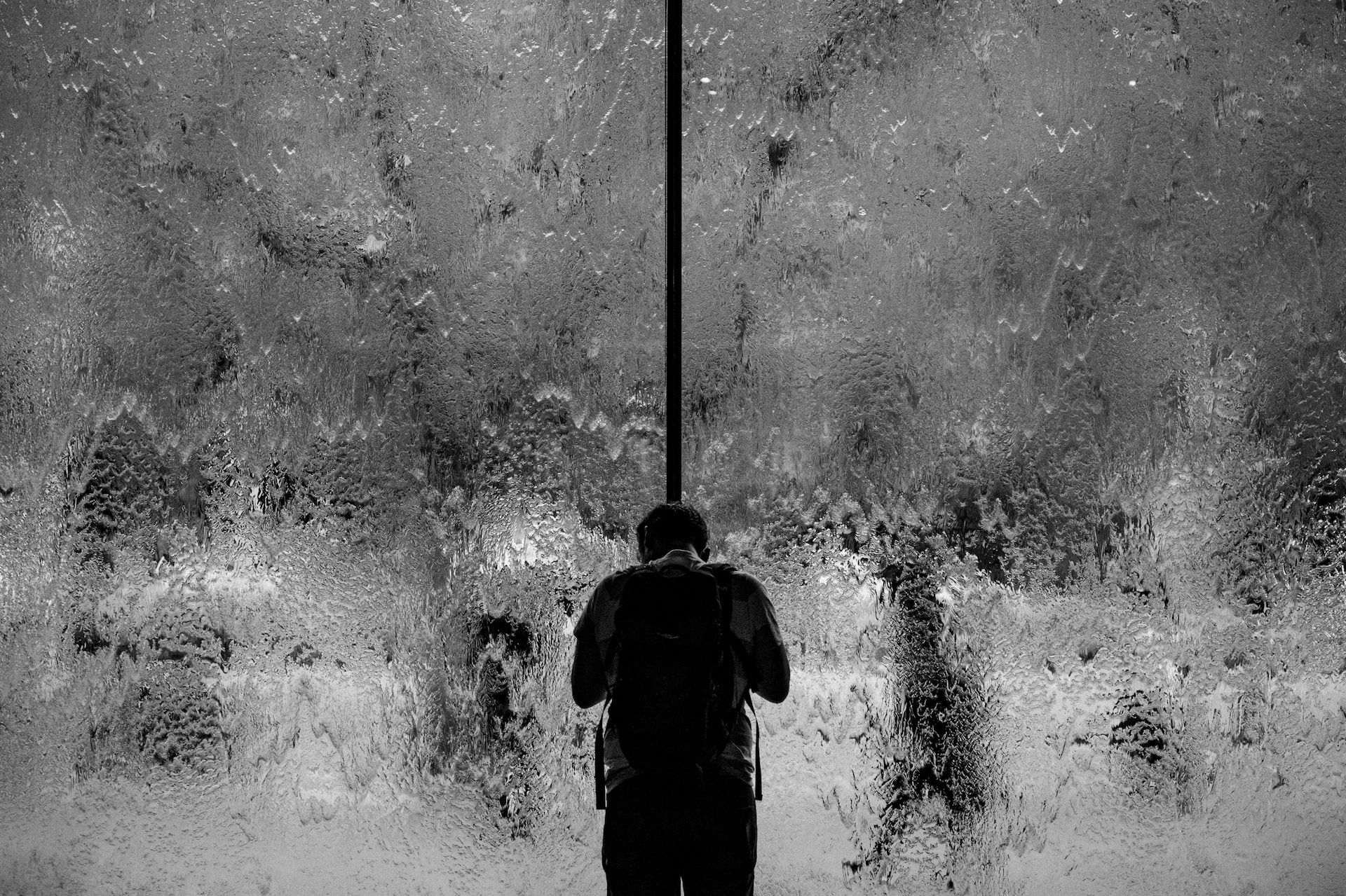 Un homme triste devant une baie vitrée troublée par de la pluie - Photo by Samuel Austin on https://unsplash.com/fr/photos/homme-debout-sur-un-mur-de-verre-avec-de-leau-qui-coule-7LJ20fadcwQ