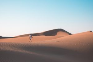 Un homme seul marche sur des dunes de sable - Photo by Yuheng Chen on Unsplash