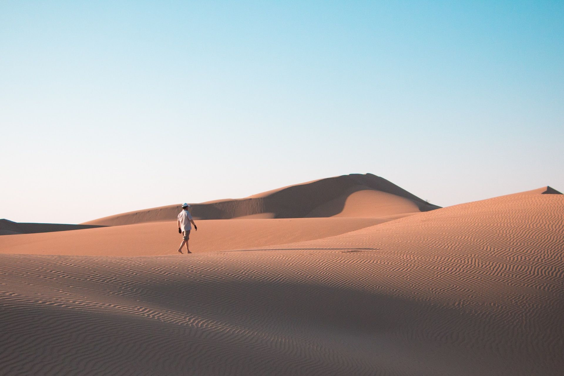 Un homme seul marche sur des dunes de sable - Photo by Yuheng Chen on https://unsplash.com/fr/photos/homme-marchant-sur-le-desert-sous-le-ciel-bleu-pendant-la-journee-Lsm-L9ahapU