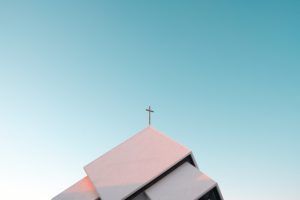 toit enneigé d'une église avec la croix qui se détache sur un ciel bleu - Photo by Akira Hojo on Unsplash