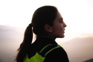 une jeune femme avec un sac à dos, de profil, regarde le lever de soleil en montagne - Photo by Alvaro Palacios on Unsplash