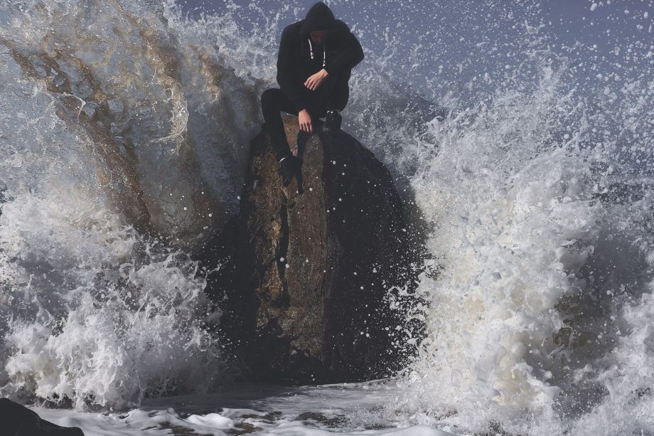 un homme sur un rocher sur lequel des vagues se brisent - Photo by Aziz Acharki on Unsplash