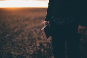 une personne, debout dans la nature à l'aube, tient sa Bible fermée en main - Photo by Priscilla Du Preez on Unsplash