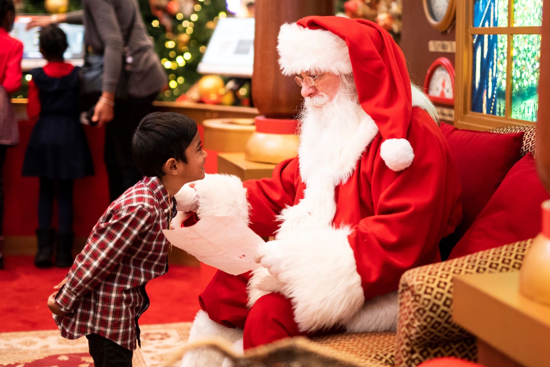 Le Père Noël lisant la liste de cadeau demandée par un enfant sur https://unsplash.com/fr/photos/garcon-debout-devant-un-homme-portant-un-costume-de-pere-noel-YZZz0_MfHto