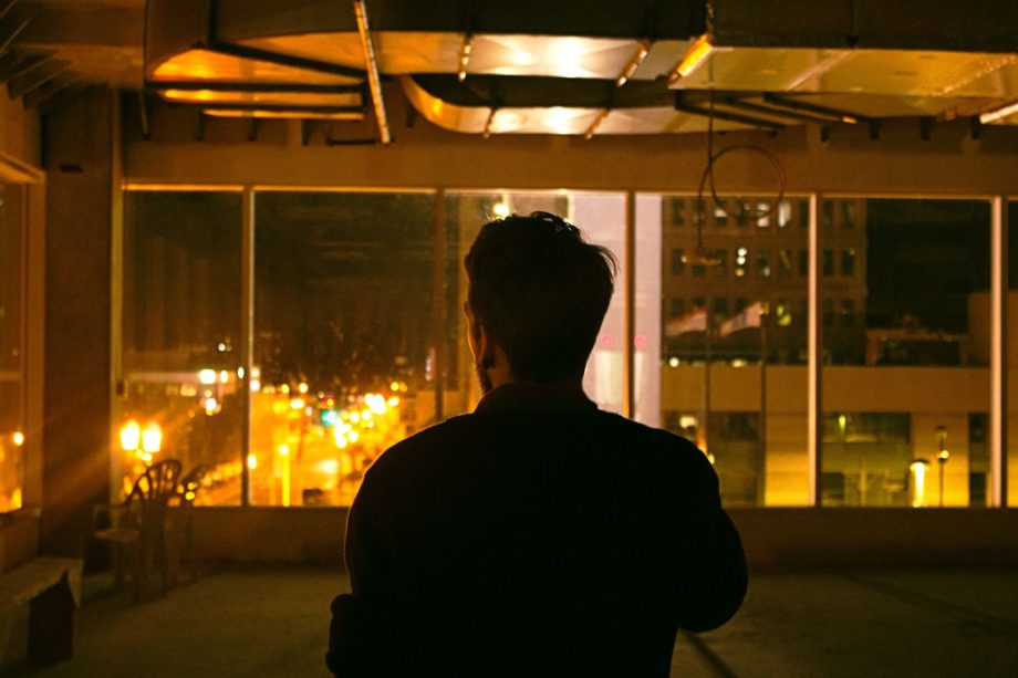 Un homme regarde la ville illuminée par la fenêtre d