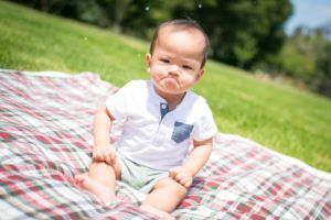 Un bébé qui a l'air en colère, assis sur une nappe de pique-nique dans un parc - Photo by Ryan Franco on Unsplash