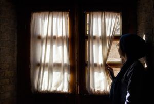 jeune femme seule regardant par la fenêtre en écartant le rideau - Photo by Mohammad Mahdi Samei on Unsplash