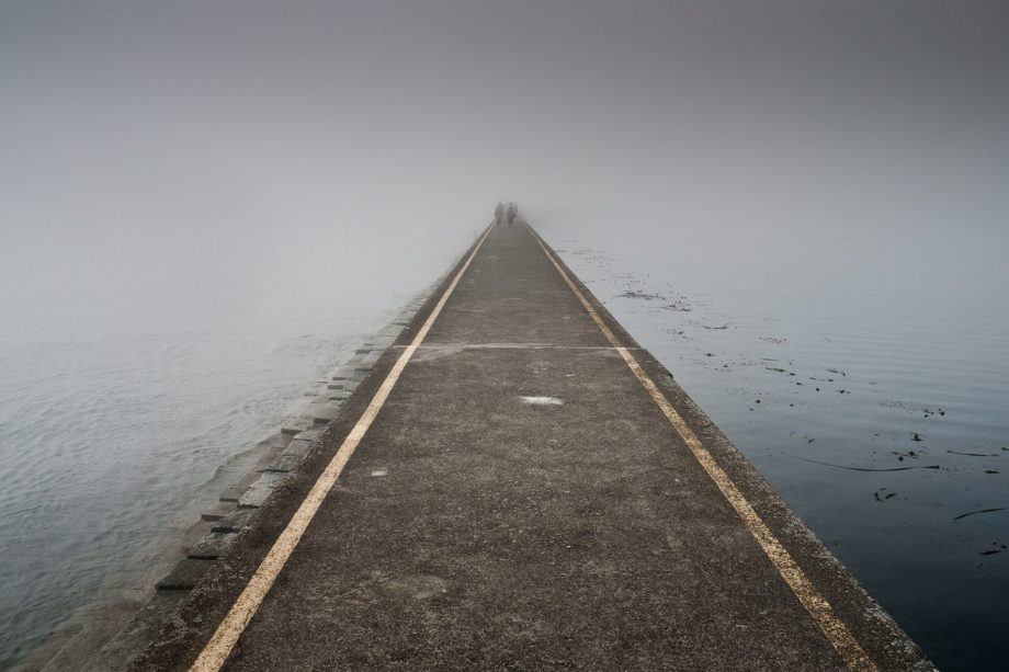 très longue digue au raz de l'ean, avec des personnes au fond, dans la brume - Photo by William Bossen on https://pixabay.com/fr/photos/jet%C3%A9e-brouillard-oc%C3%A9an-chauss%C3%A9e-1850884/