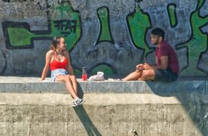 jeune homme et jeune fille assis sur un quai - Photo by Pascal Bernardon on Unsplash