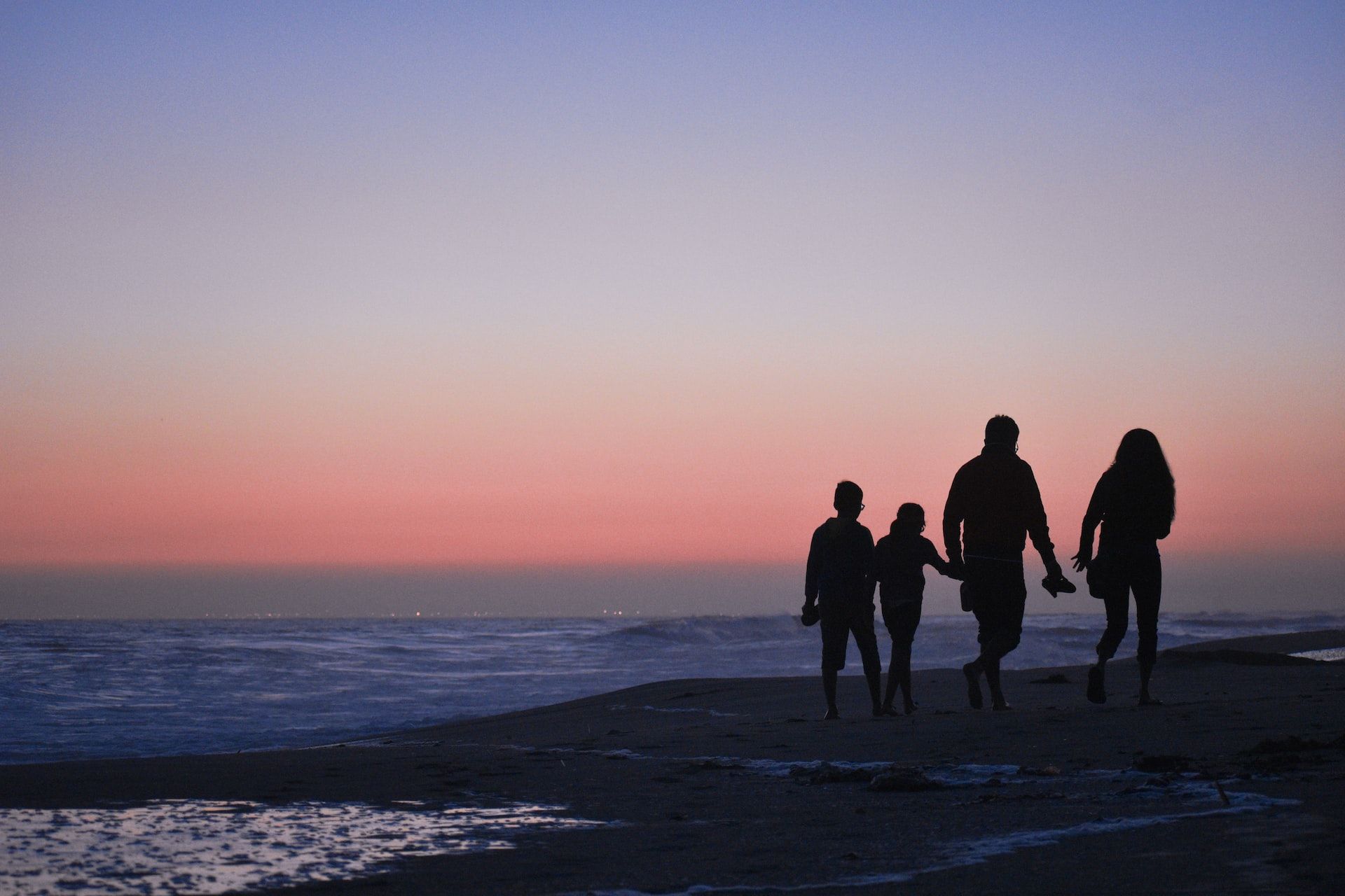famille marchant en bord de mer au coucher du soleil - Photo by Sarah Medina on Unsplash
