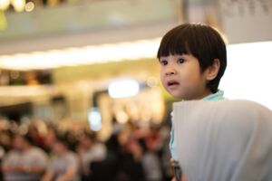 Un jeune enfant regarde avec un peu de frayeur au loin par dessus une foule - Photo de Hobi industri sur https://unsplash.com/fr/photos/garcon-portant-un-haut-bleu-sarcelle-ztGjwtWU5y4
