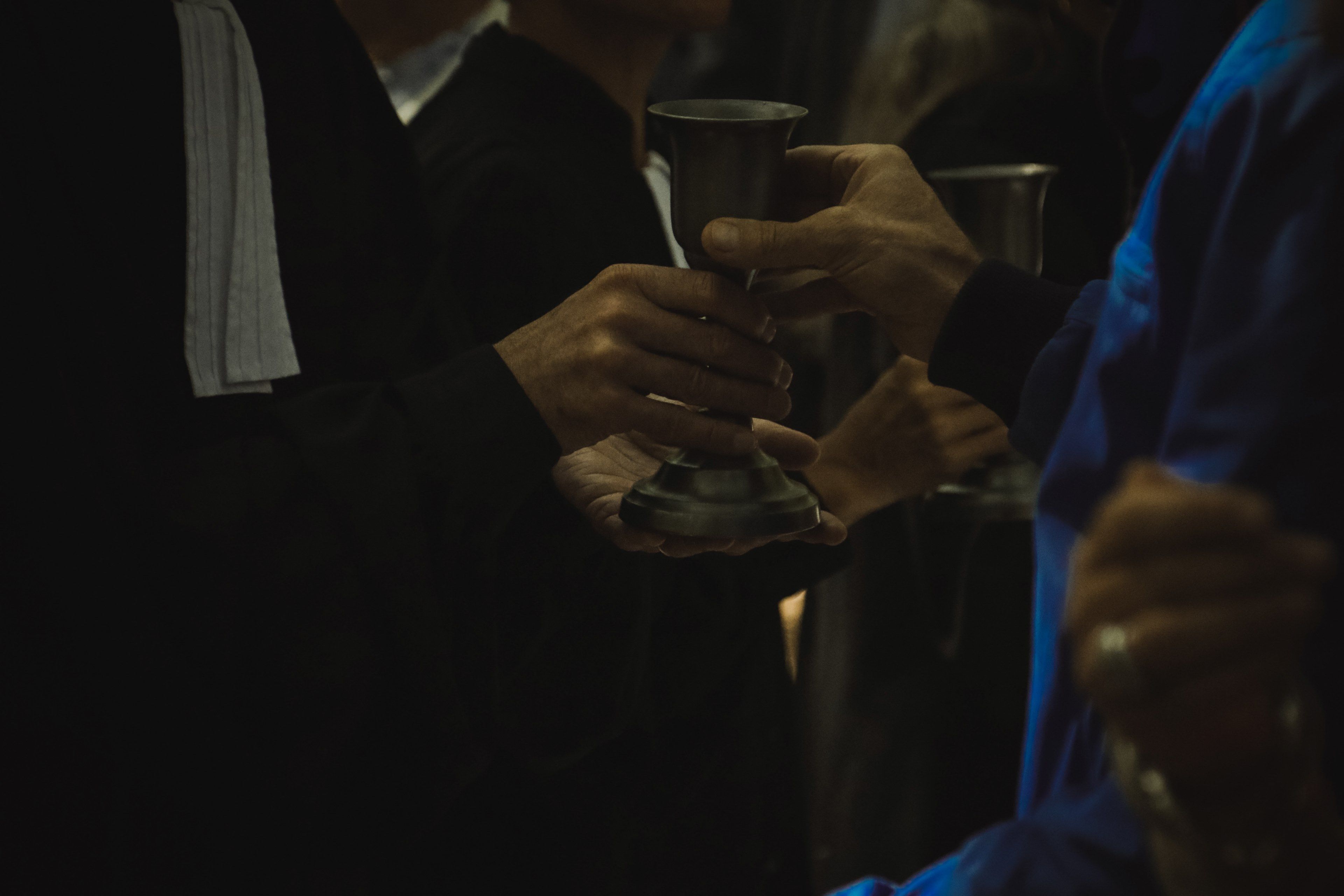 main d'un pasteur passant la coupe à une personne - Photo by Jametlene Reskp on Unsplash